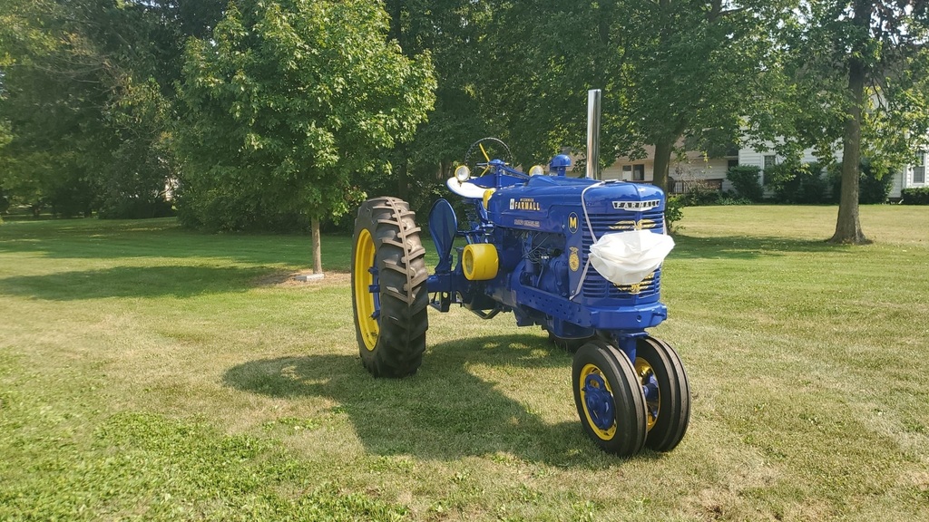 Blue antique tractor with large mask on the front.
