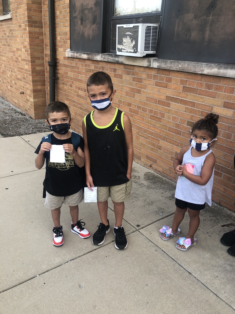 Three children waiting for bus with masks on